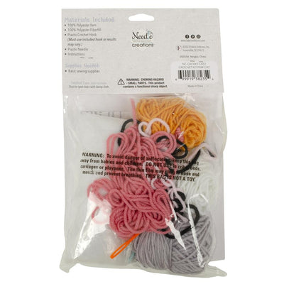 A flat lay of the Needle Creations kit: bundles of soft yarn, a bag of polyester stuffing, a crochet hook, and the clear instructional manual