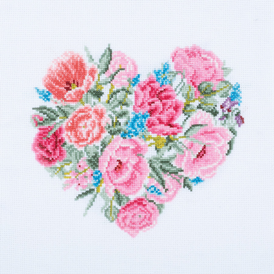 Cross stitch kit image showing a heart-shaped design with a floral pattern in pink, blue, and green colors on a white background.