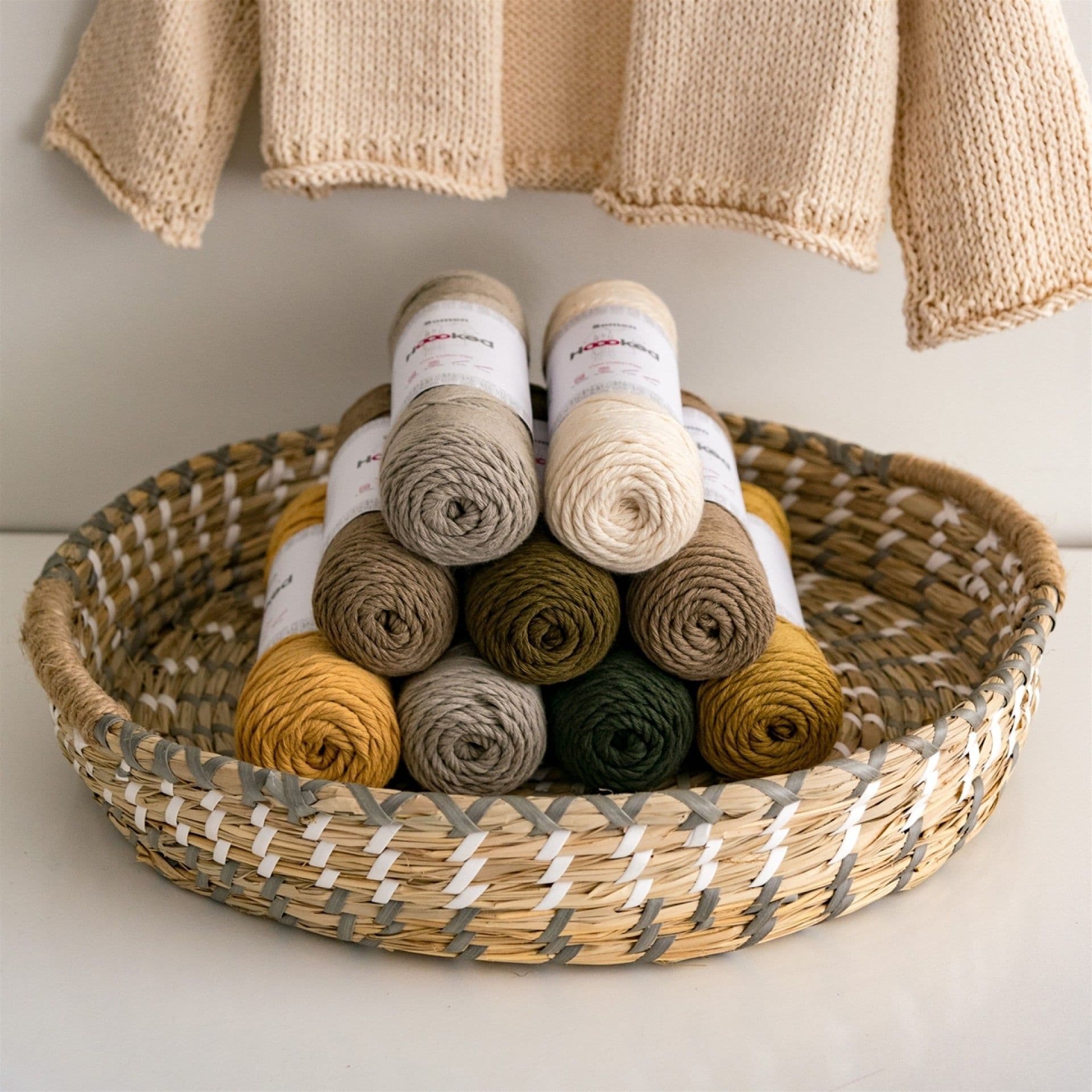A basket containing multiple skeins of Hoooked Somen DK yarn in various natural colors.
