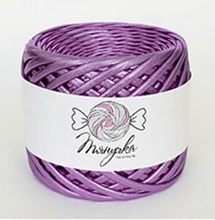 A spool of metallic mauve purple yarn with a label that has a heart and wings graphic on it, set against a blurred bokeh background.