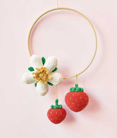 Several crocheted flowers and strawberries strung together as a colorful, nature-themed nursery hoop.