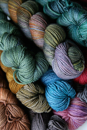 A collection of skeins of Malabrigo Finito Yarn in various colors arranged closely together.