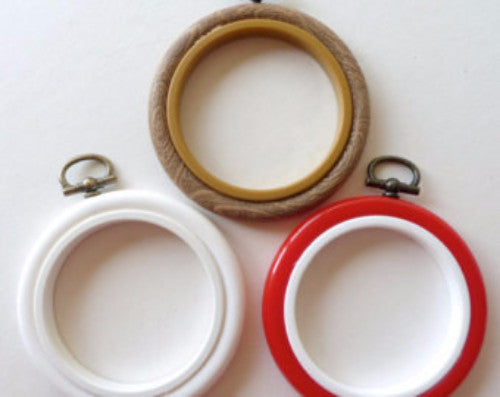 Three embroidery hoops in white, beige, and red colors, with plastic rims and metal screws for attachment.

A vibrant 3-inch circular plastic embroidery hoop with a matching adjustable tension screw, showing its smooth and colorful finish
