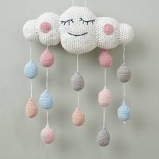 The book contains twelve exclusive English-language patterns for both knitting and crochet, featuring a range of newborn clothing, soft toys, nursery mobiles, and bedding accessories in a soft, modern aesthetic.