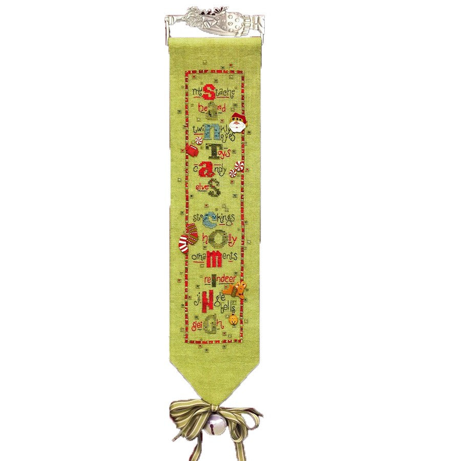 A green fabric with Christmas-themed embroidery, featuring text 'Santa's Coming' and decorative elements like a bell, stocking, and snowflakes.

The Art to Heart 'Santa's Coming' cross-stitch chart featuring a vertical Santa Claus design and a pack of colorful, handcrafted designer buttons.