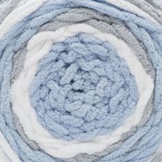 A ball of Bernat Baby Blanket Stripes yarn in light blu, gray, and white colors.
