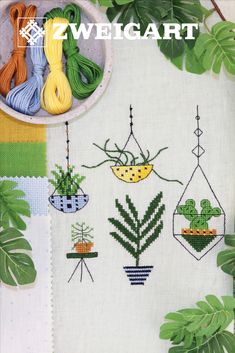 An inspirational cross-stitch leaflet titled 'Botanical Balance,' featuring a variety of miniature houseplant designs such as ferns, succulents, and hanging ivy. The booklet includes detailed counted cross-stitch charts, fabric suggestions, and a comprehensive color legend for both DMC and Anchor embroidery floss