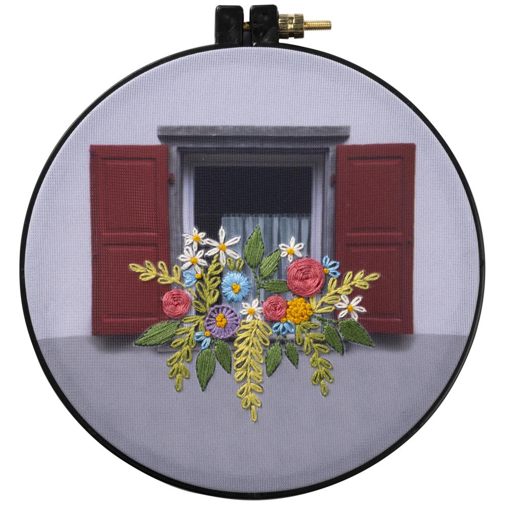 Round embroidery kit depicting a flower box scene with a red door and white flowers, finished needlework presented on a 6-inch plastic hoop.

A beginner-friendly Bucilla stamped embroidery kit featuring the 'Flower Box' design. The kit includes a photographic stamped polyester broadcloth with the floral design clearly marked, colorful cotton embroidery floss, an embroidery needle, and a 6-inch blue plastic hoop that serves as both your workspace and your final display frame