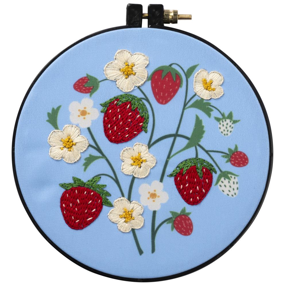 A beginner-friendly Bucilla stamped embroidery kit titled 'Strawberry Field.' The image shows a charming design of ripe red strawberries and delicate white blossoms. The kit features a 6-inch plastic hoop, colored printed polyester broadcloth, vibrant cotton embroidery floss, and a needle, perfect for a quick and rewarding 15cm round project