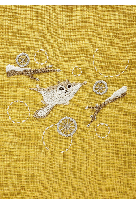 The completed Chicchi animal embroidery, showcasing a flying squirrel, professional texture and soft, forest-inspired color on mustard yellow 100% linen background.