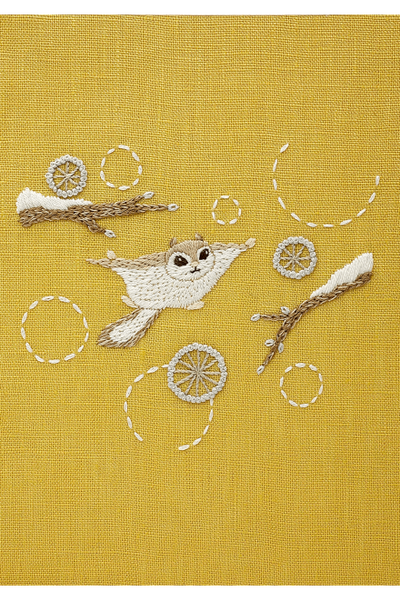The completed Chicchi animal embroidery, showcasing a flying squirrel, professional texture and soft, forest-inspired color on mustard yellow 100% linen background.