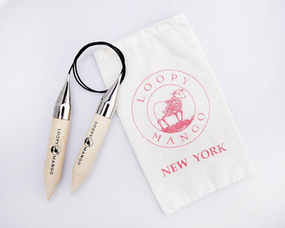 A pair of 25mm Loopy Mango circular knitting needles made of light-colored birch wood with a flexible clear connecting cord