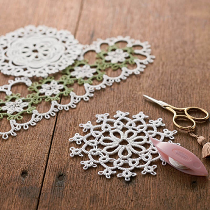 Close-up of a Flora Series tatting shuttle by Clover, showcasing the soft pastel color and the delicate decorative flower motif on the durable, lightweight body.