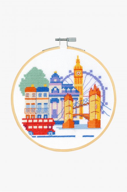Cross stitch kit depicting a colorful image of London landmarks, including a bus, a double-decker bus, and a clock tower, on a white background.