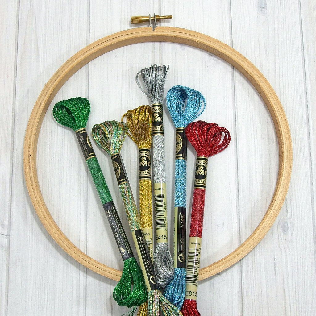 A collection of metallic threads in various colors displayed on a wooden spool with a white background.