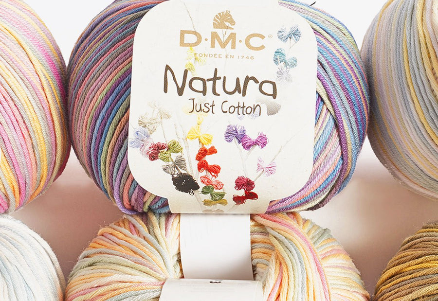 Multiple skeins of DMC Natura Multico Cotton yarn in a variety of colors, arranged in a circular pattern with the DMC brand tag visible.