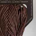 A donut of Daruma Sasawashi Flat yarn, showing its sleek, ribbon-like structure and the natural, soft-gold luster of Kumasasa bamboo paper in dark brown colour