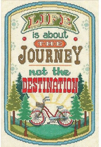 An inspirational Design Works counted cross-stitch kit featuring the quote 'Life is about the Journey, not the Destination.' The artwork depicts a vintage woodie station wagon with a surfboard and luggage on top, driving through a scenic landscape. The kit includes 14-count white Aida cloth, pre-sorted cotton threads, a needle, and easy-to-follow instructions