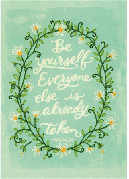 A bright and whimsical Dimensions embroidery kit featuring the phrase 'Be Yourself' in stylized, colorful lettering. The text is surrounded by a playful assortment of hand-drawn flowers, stars, and dots in a palette of pink, orange, yellow, and turquoise. The design is pre-printed on a soft muslin fabric, and the kit includes all necessary embroidery threads and a needle.