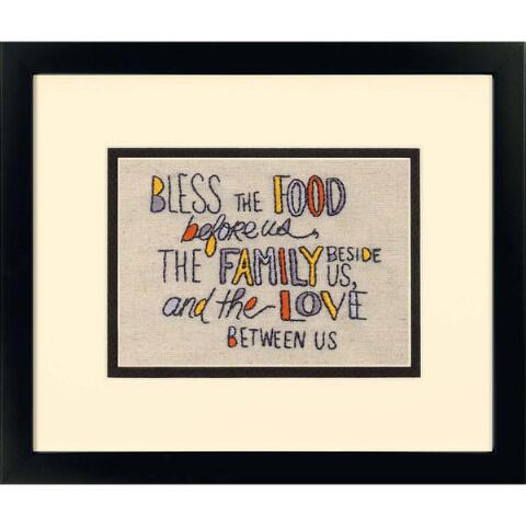 A serene Dimensions embroidery kit featuring a traditional table blessing surrounded by elegant leafy branches and small floral buds. The quote is written in a combination of classic serif and flowing script fonts. The design is pre-printed on high-quality linen fabric and includes earthy-toned embroidery floss and a needle for a 7x5 inch finished piece