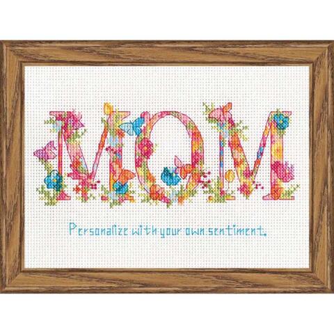 A sweet and sentimental Dimensions Learn-a-Craft cross-stitch kit designed for 'Mom.' The design features the word 'Mom' in elegant script, surrounded by a delicate garden of colorful flowers and green leaves. The kit includes 14-count white Aida fabric, pre-sorted cotton floss, a needle, and easy-to-follow instructions for a 5x7 inch finished piece