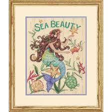 An elegant Dimensions counted cross-stitch kit titled 'Sea Beauty.' The design features a serene mermaid with flowing hair swimming among colorful coral, sea shells, and ocean flora. The kit includes 14-count natural-colored Aida cloth, pre-sorted embroidery threads in aquatic tones, a needle, and a detailed pattern sheet