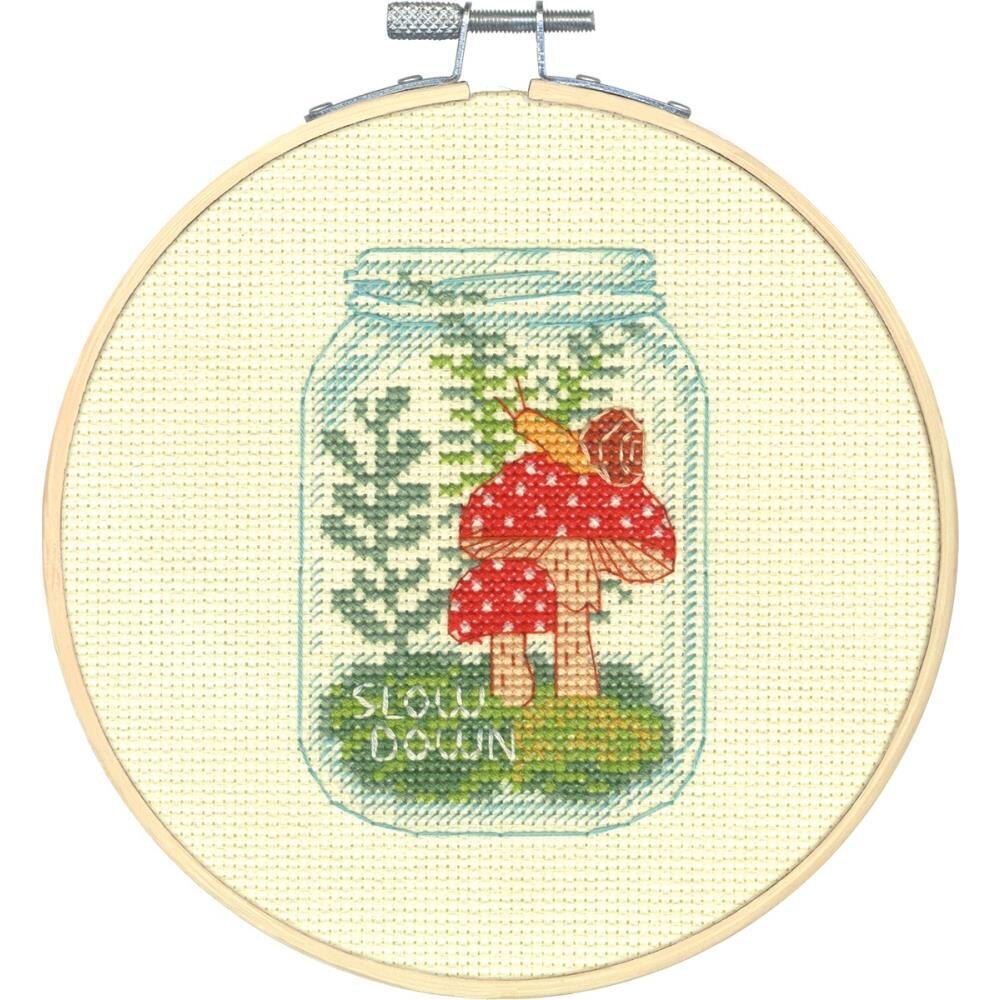 A beginner-friendly Dimensions cross-stitch kit titled 'Slow Down.' The design features a colorful, whimsical snail and the phrase 'Slow Down' in a friendly font. The kit includes 14-count white Aida fabric, a 6-inch bamboo embroidery hoop, pre-sorted embroidery thread, a needle, and instructions.
