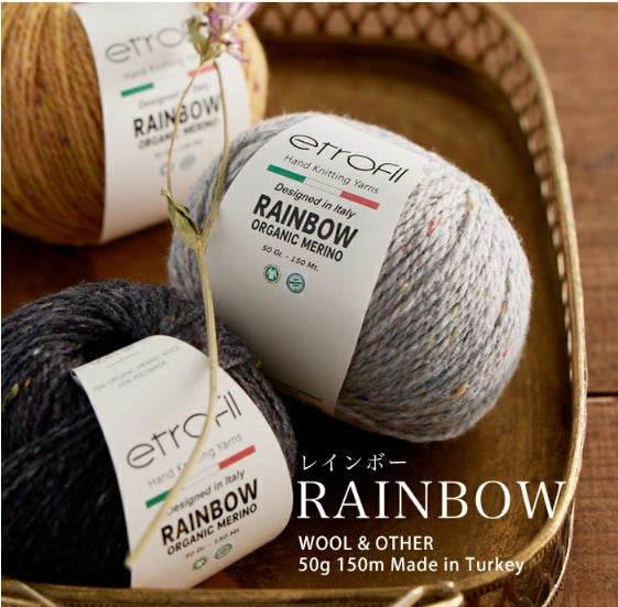 Balls of multicolored merino wool yarn with labels indicating the brand and information about the product, placed on a wooden surface.