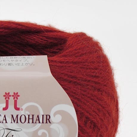A 25g ball of Hamanaka Alpaca Mohair Fine yarn, showcasing its soft, fuzzy halo and fine, delicate strand. The image highlights the airy texture created by the blend of goat mohair and high-grade alpaca, perfect for knitting or crocheting lightweight, fluffy wearables like scarves, vests, and cardigans Ravlery Red colour