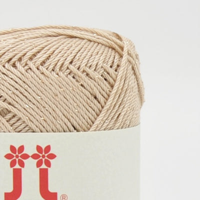 A compact ball of Japanese Aprico Lame cotton yarn, highlighting the vibrant color and the elegant, understated sparkle of the integrated metallic fibers in Ecru Beige