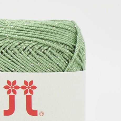 A compact ball of Japanese Aprico Lame cotton yarn, highlighting the vibrant color and the elegant, understated sparkle of the integrated metallic fibers in spring green colour