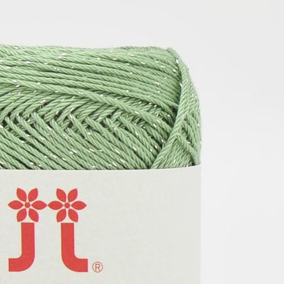 A compact ball of Japanese Aprico Lame cotton yarn, highlighting the vibrant color and the elegant, understated sparkle of the integrated metallic fibers in spring green colour