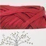 Close-up of Hamanaka Eco Andaria yarn showing its smooth, flat tape texture and silky raffia sheen. 
In scarlet red colour