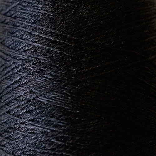 Close-up of the smooth, liquid-like silk thread of Pierrot Silk100, highlighting the fine lace weight and reflective quality in black colour