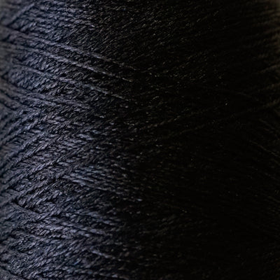 Close-up of the smooth, liquid-like silk thread of Pierrot Silk100, highlighting the fine lace weight and reflective quality in black colour