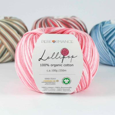 A skein of pink Lollipop brand organic cotton yarn with a label showing the brand name and yarn type, surrounded by other skeins of yarn in the background.
