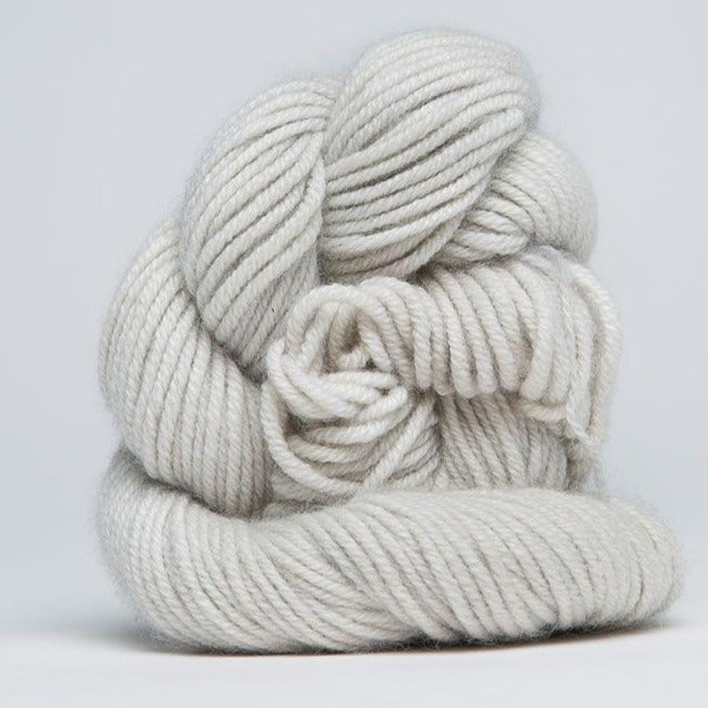 A skein of Jade Sapphire 100% Cashmere Yarn in a hand-dyed colorway, featuring shades silver white colour