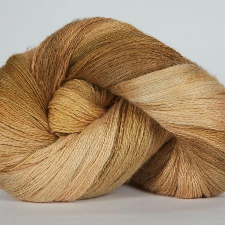 Jade Sapphire hand-dyed 50% silk and 50% yak lace yarn from Mongolia; a 100g skein with 700 yards for premium lace knitting."
"Close-up of hand-dyed Jade Sapphire exotic fiber yarn in Golden yellow to brown tone, showing the unique tonal variations and silken luster of the yak-silk blend."