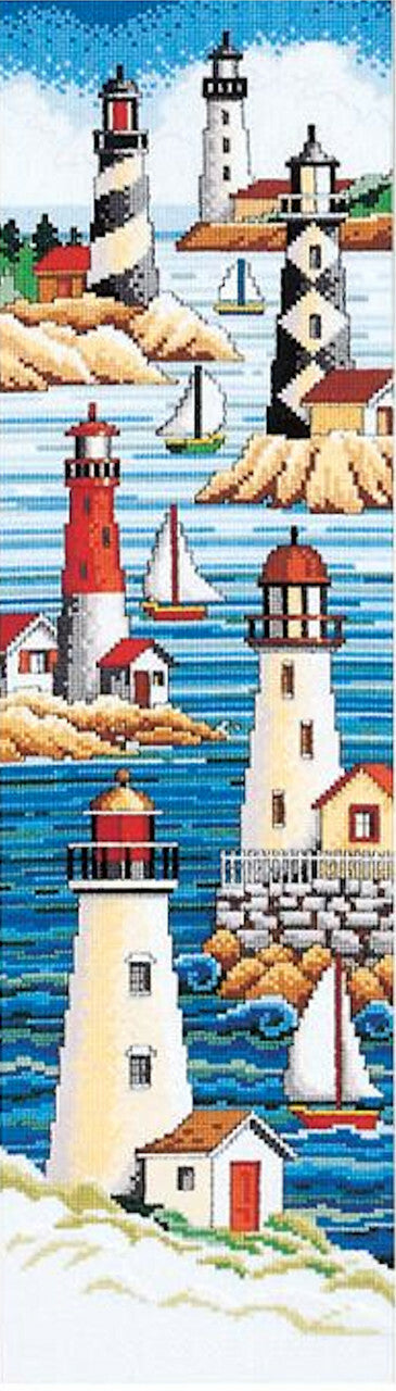 A cross stitch kit image depicting a lighthouse and sailboats on a blue ocean background, with houses on a rocky bluff.