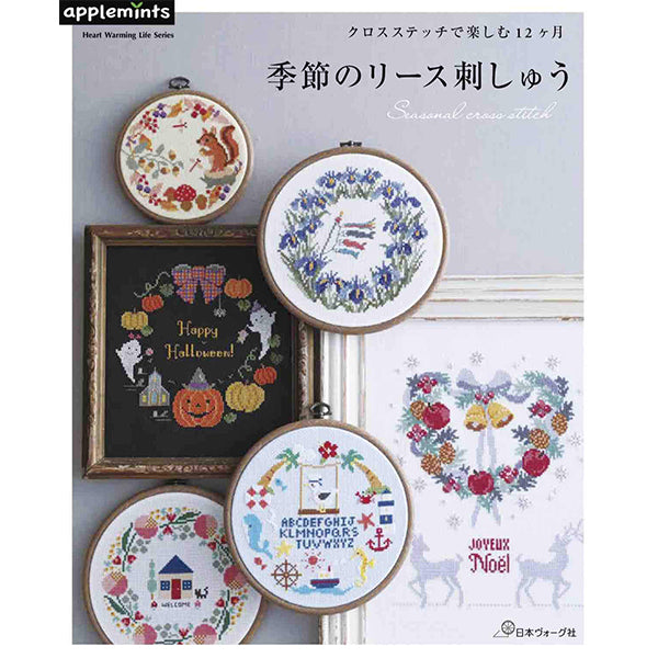 A book titled 'Seasonal Cross Stitch' displaying various cross stitch patterns with seasonal themes, predominantly in Japanese, with an image of a pumpkin and flowers on the cover.