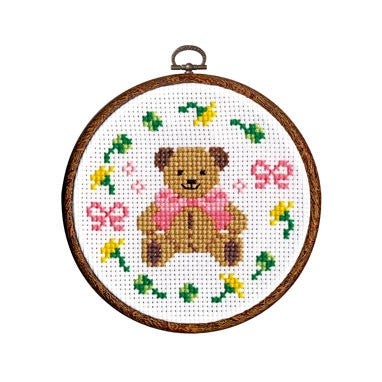 Cross stitch kit depicting a bear with a pink bow on a green and floral background in an embroidery hoop.

The Olympus Bear Cross Stitch kit packaging, featuring a cute illustrated brown bear design and a vibrant 6-inch embroidery hoop