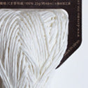 "A donut of Daruma Sasawashi Flat yarn, showing its sleek, ribbon-like structure and the natural, soft-gold luster of Kumasasa bamboo paper in white colour.