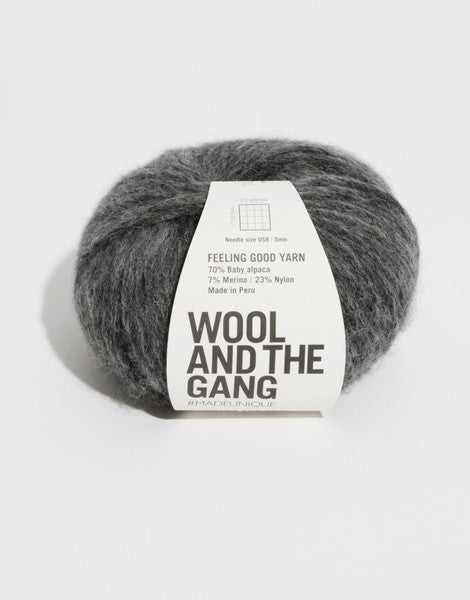 A 50g ball of Wool and the Gang Feeling Good yarn, showing its signature fluffy, brushed texture and voluminous air-blown structure in tweed dark grey colour.