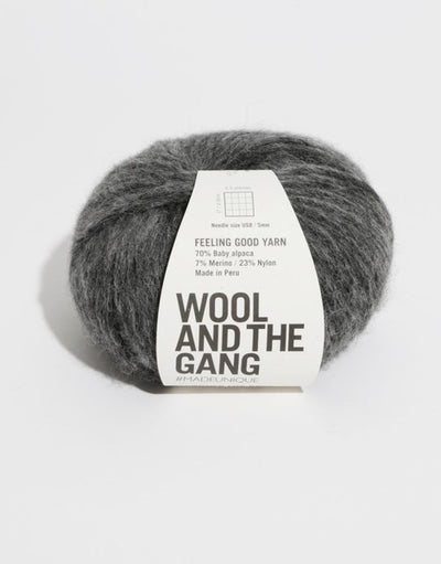 A 50g ball of Wool and the Gang Feeling Good yarn, showing its signature fluffy, brushed texture and voluminous air-blown structure in tweed dark grey colour.