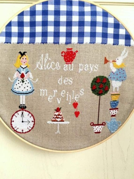A professional-grade cross-stitch chart by Lilli Violette titled 'Alice.' The high-definition design features a whimsical, vertically-oriented interpretation of Alice in Wonderland, featuring an artisanal central Alice figure surrounded by soulful motifs like the White Rabbit and tea party elements.
