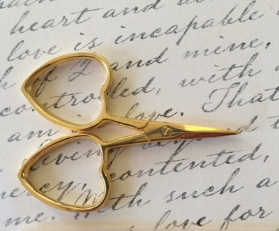 A pair of professional-grade miniature embroidery scissors featuring iconic heart-shaped handles in gold coloured