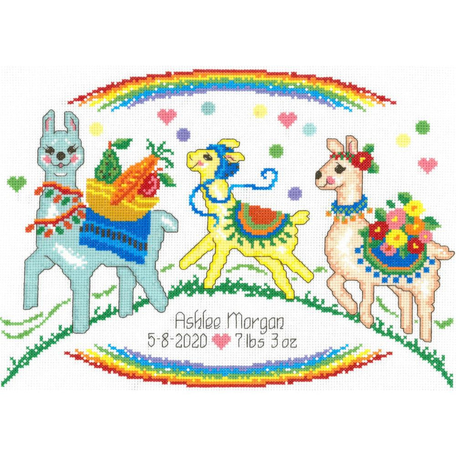 A cross stitch kit depicting three colorful llamas on a rainbow-filled background with a green field and colorful banners, designed by Ursula Michael.