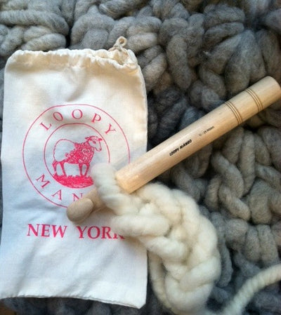 A large crochet hook lying on a textured surface, next to a white drawstring bag with the Loopy Mango brand logo.

The Loopy Mango 25mm hook being used to crochet a thick, chunky white wool blanket, showing the hook catching the jumbo fibers easily

Extreme Crochet Tools