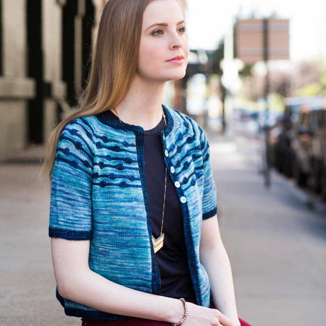 inside pages of Malabrigo Book 14 showing a detailed technical chart and a high-resolution photo of a cabled cardigan.