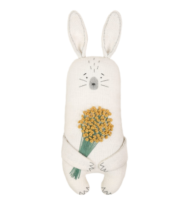 A sewing kit depicting a white animal, resembling a rabbit, with ears on top and a tuft of yellow flowers in its hands.